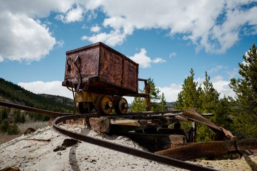 An ore cart sits on some bent track, high out of the mine it belongs to.