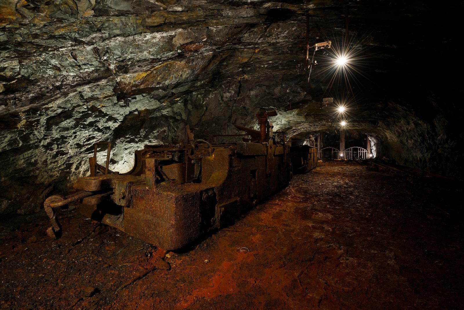 A chain of two abandoned mine locomotives sit still, parked and untouched for decades in front of the shaft.