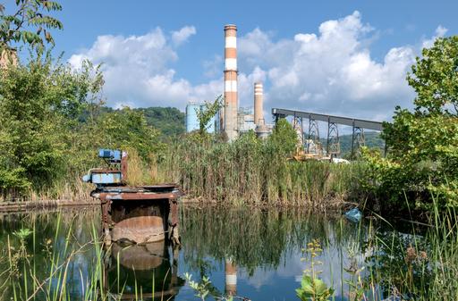 At an abandoned power plant, a water treatment clarifier sits idle and overgrown.