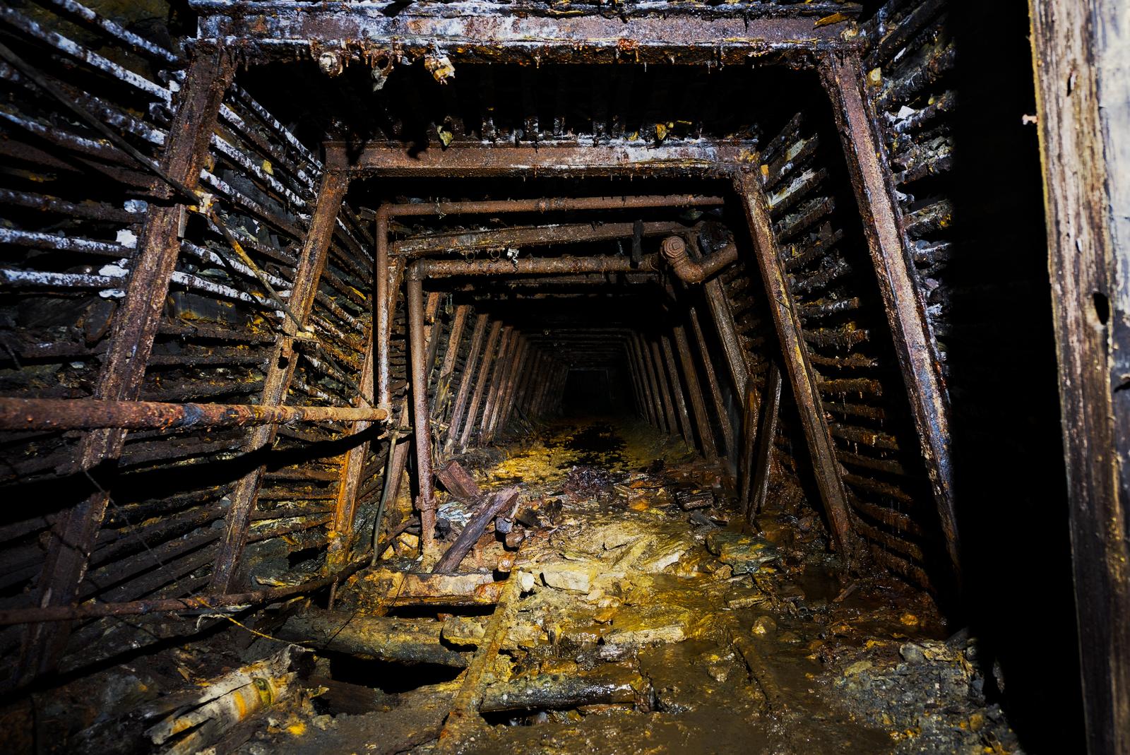 A coal mine tunnel which has been resourcefully braced with rails to support the roof.