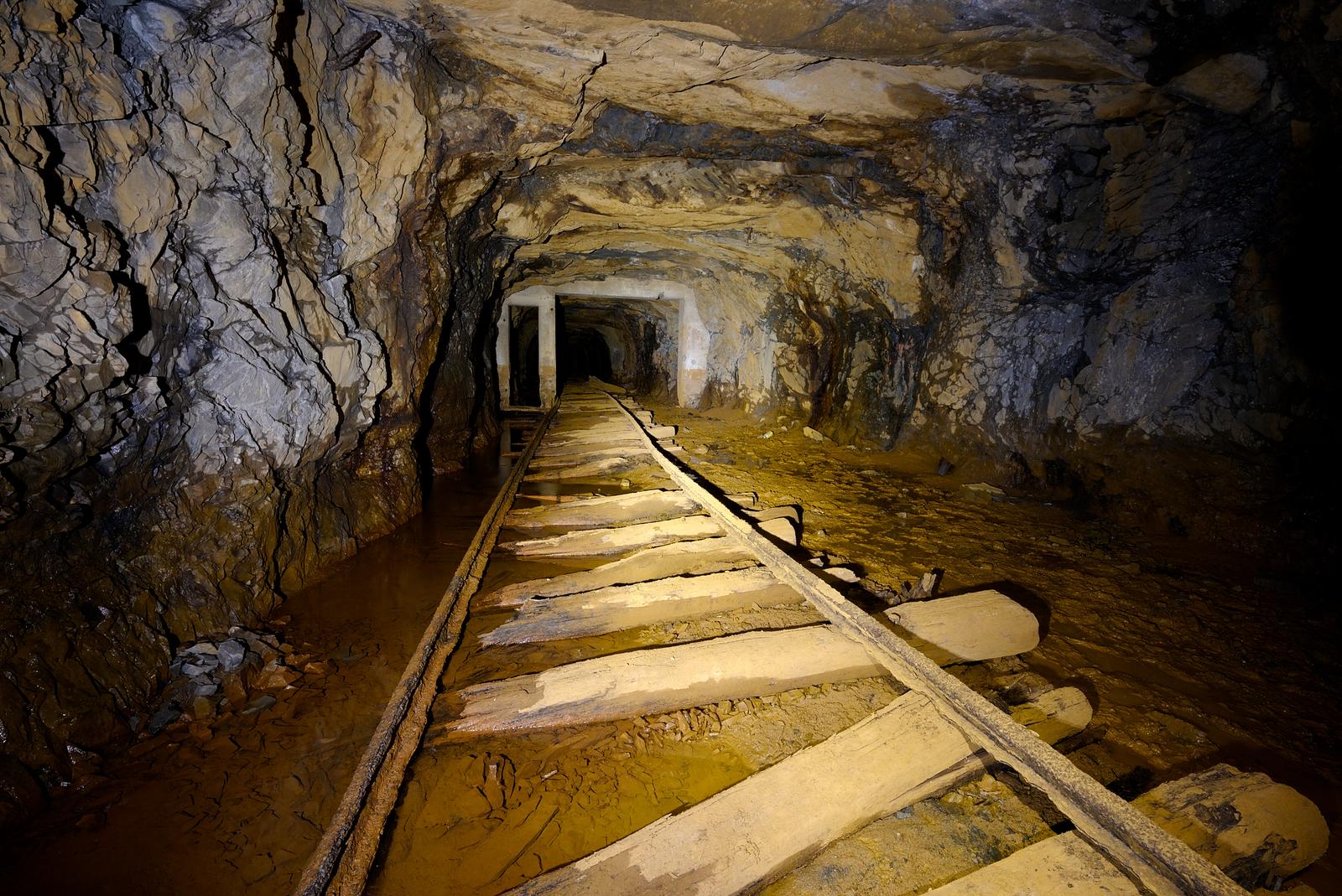 In an abandoned mine, the main rail line slides into the gutter.